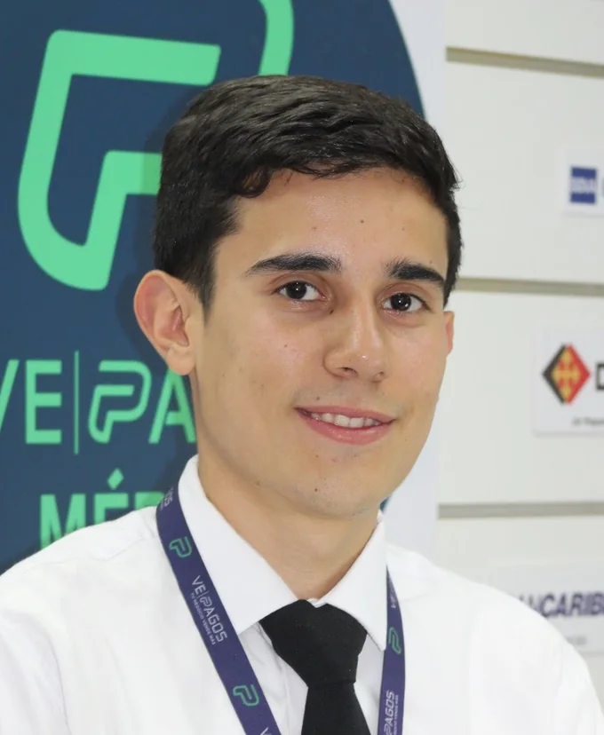 Adrian Linares, de camisa blanca y corbata, en el stand de una feria de servicios financieros.